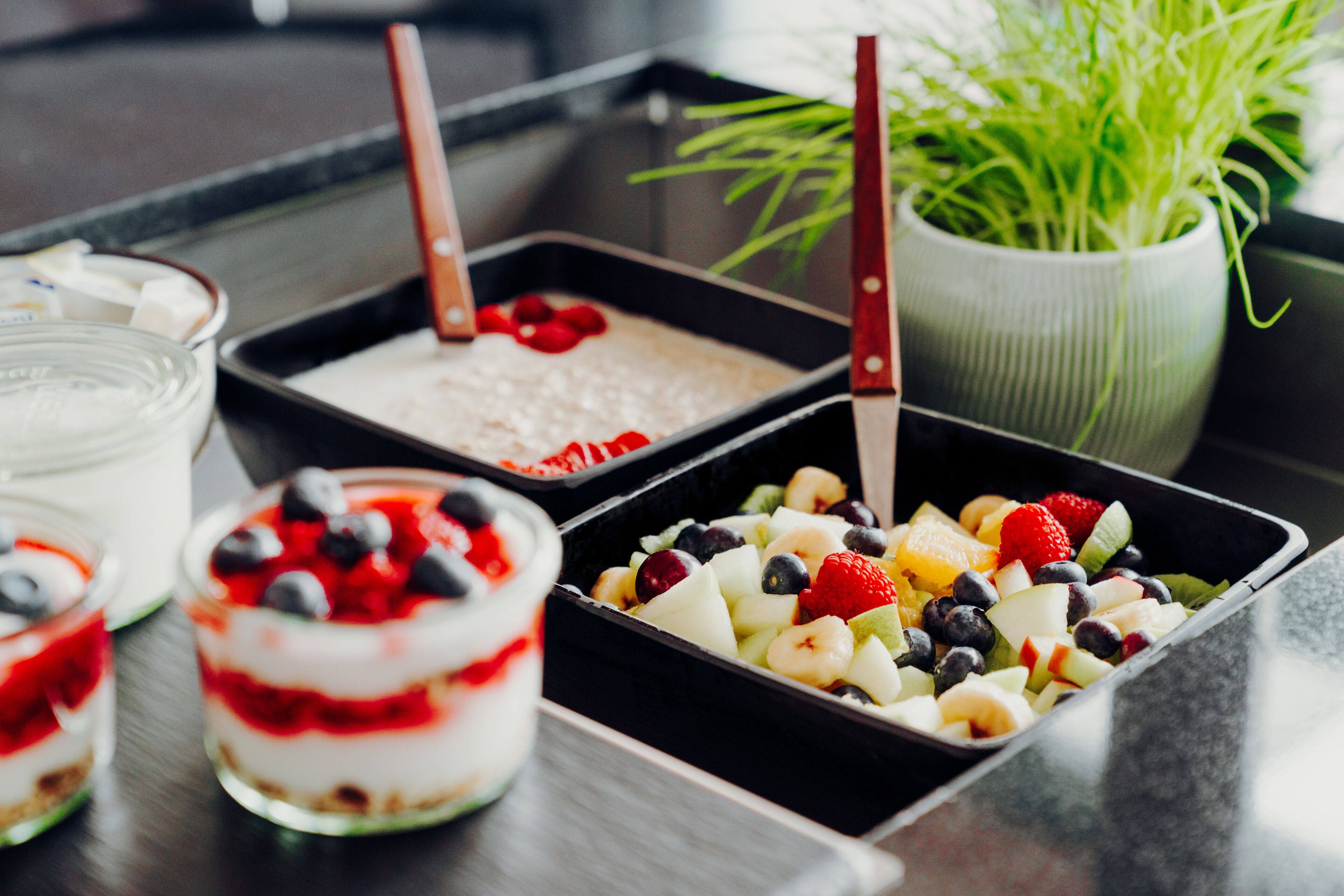 Diversos doces, incluindo uma parfait em camadas, salada de frutas e sobremesa com chantilly e frutas vermelhas.