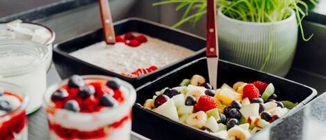 Diversos doces, incluindo uma parfait em camadas, salada de frutas e sobremesa com chantilly e frutas vermelhas.