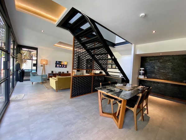 Enjoy meals at the dining table, surrounded by a comfortable seating area with a sofa and TV.