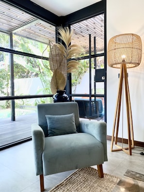 Relax in a serene space with a view of lush greenery, featuring a comfortable armchair and ambient lighting.