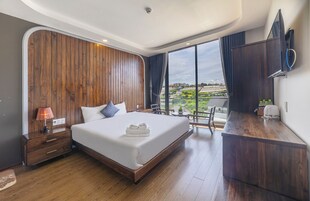 Quarto de hotel moderno com uma cama grande, paredes em painel de madeira, uma mesa de trabalho e vista para a cidade.