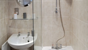 A bathroom with a sink, mirror, and shower.