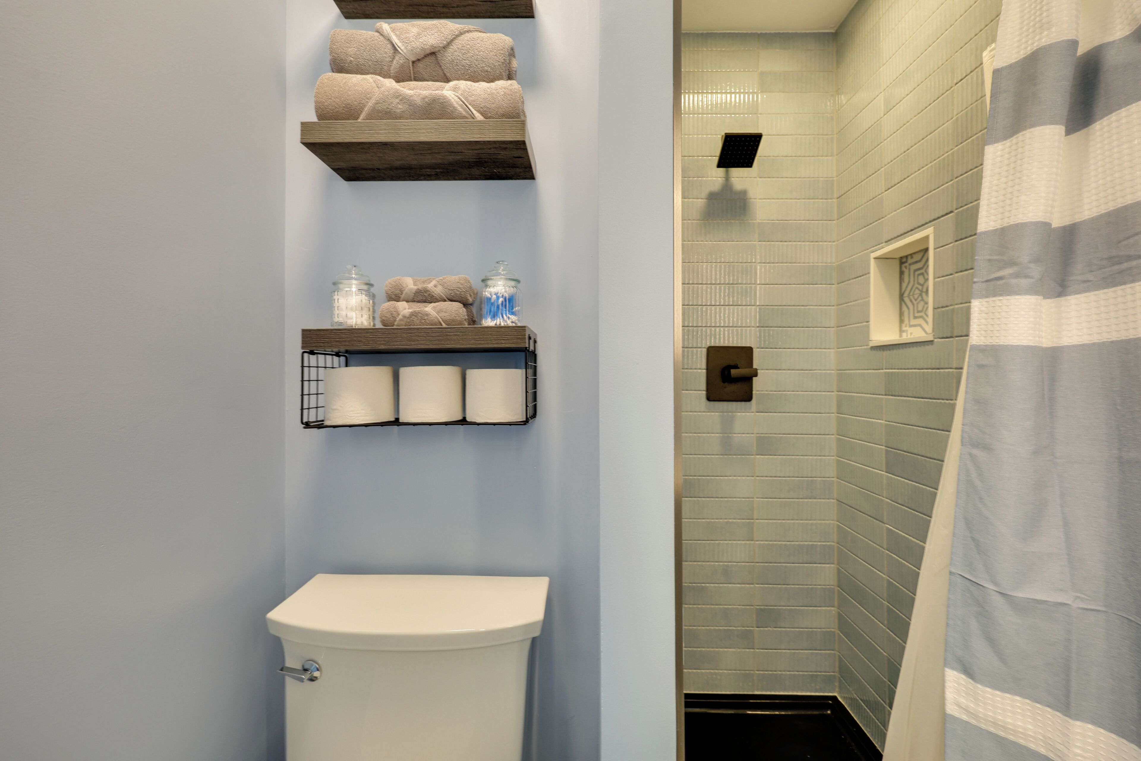 A bathroom with a toilet, towel racks, and a shower area.