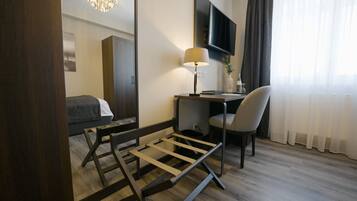 A hotel room with a bed, desk, chair, TV, and a mirror.