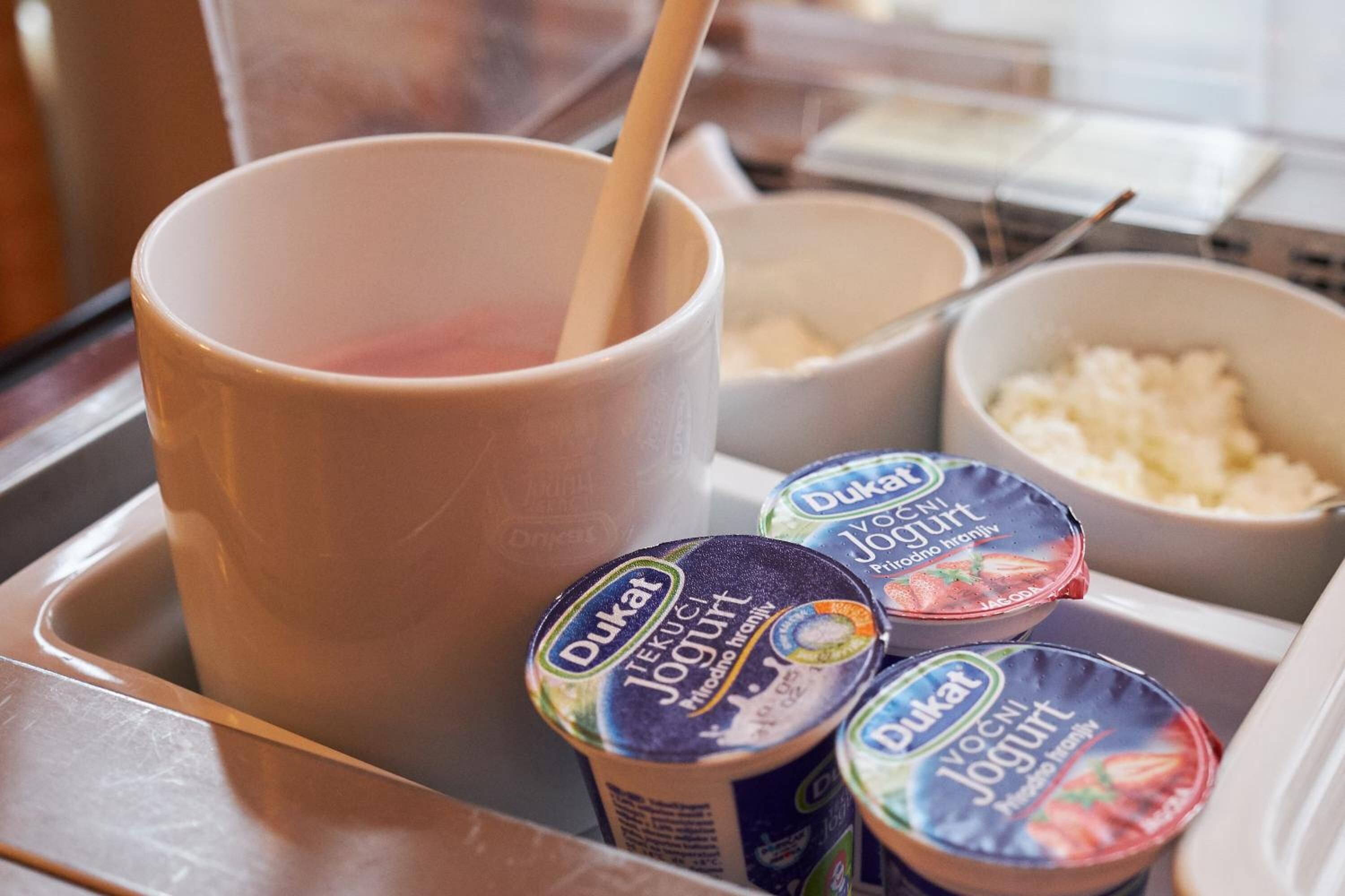 Un comptoir de cuisine avec une grande tasse, un bol de riz et trois pots de yaourt.