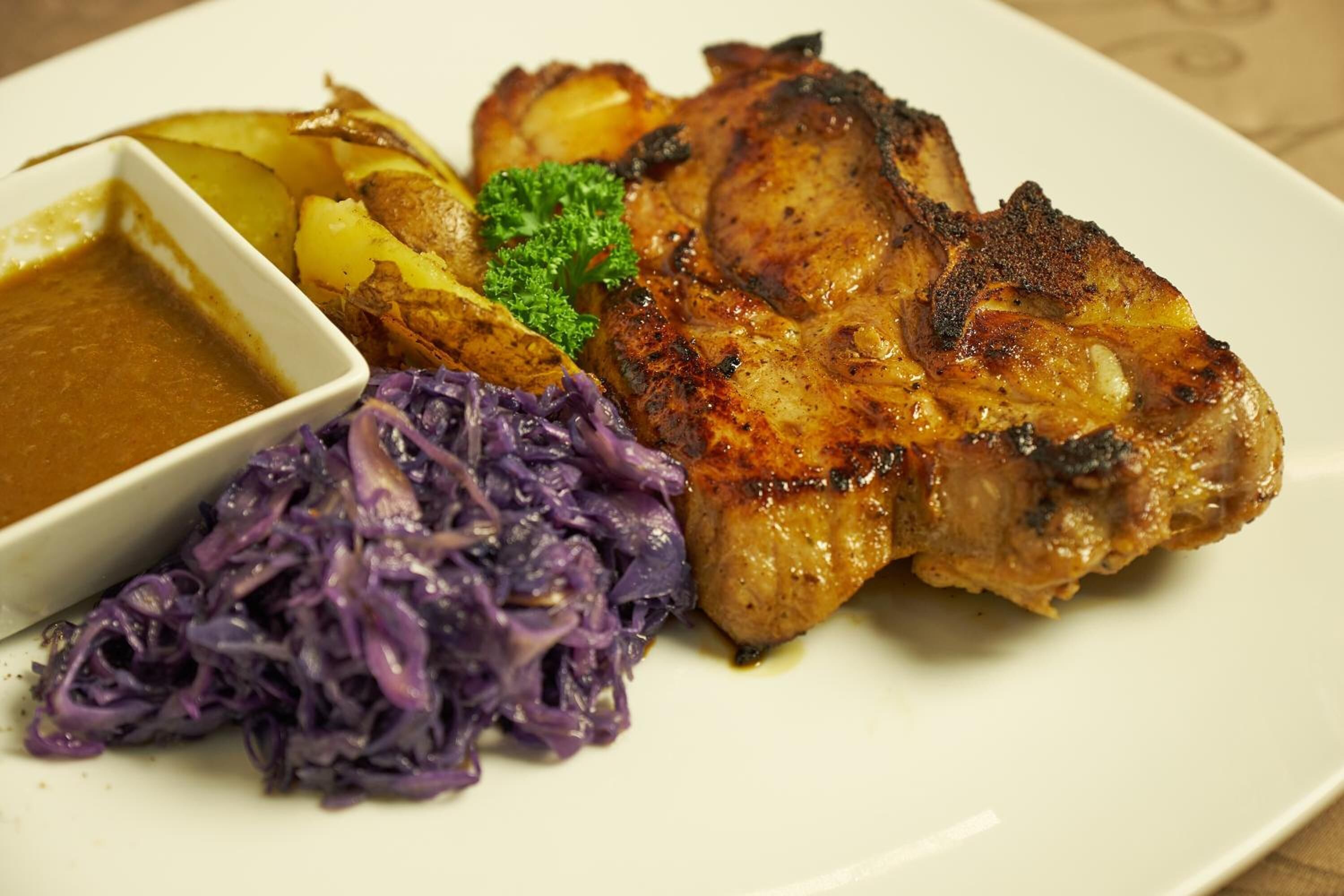 A plate with roasted pork, potatoes, and red cabbage.