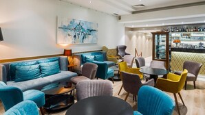 Un'area lounge moderna con un divano componibile, tavolini rotondi e sedie colorate.