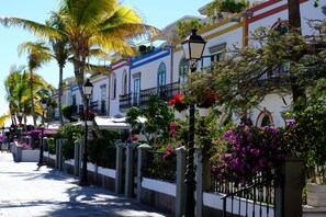 A street lined with palm trees and buildings with balconies. - Apartment 1ºB "Spectacular views of the ocean and the Puerto de Mogán marina" (Lomo Quiebre)