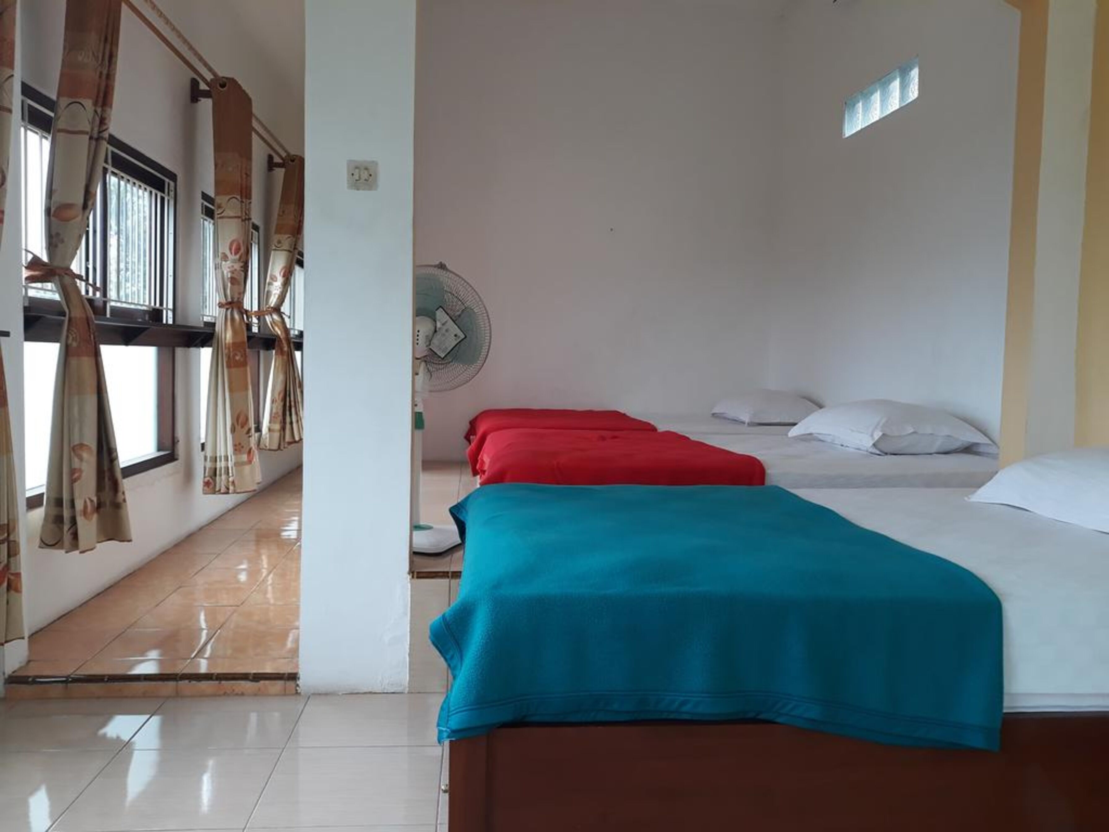 Una habitación con dos camas, un ventilador y cortinas.
