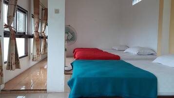 Una habitación con dos camas, un ventilador y cortinas.