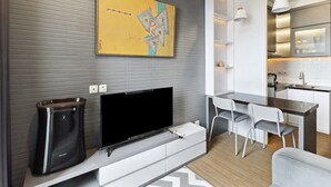 Una cocina moderna con zona de comedor, televisor de pantalla plana y cafetera.