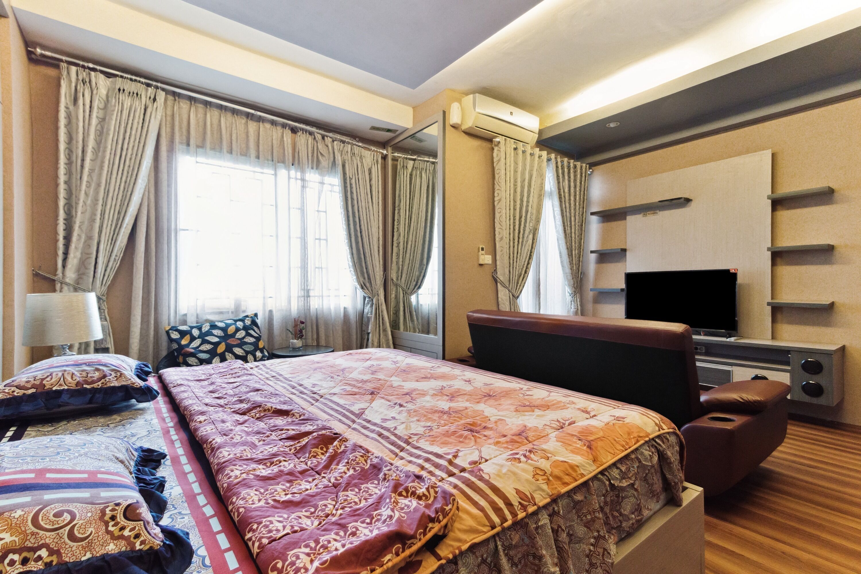 A hotel room with a large bed, a TV, a sofa, and a desk.