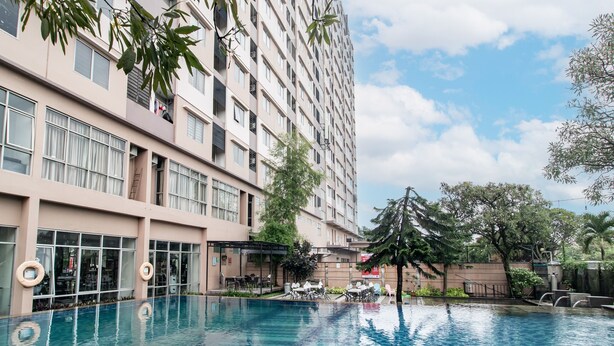 Un hotel de varios pisos con piscina, zona de estar al aire libre y vistas a la vegetación circundante.