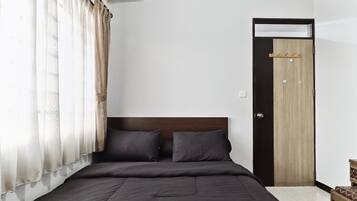 Un dormitorio con una cama, una puerta de madera y una ventana con cortinas.