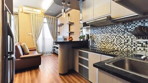 Una cocina compacta con encimera negra, estufa integrada y salpicadero azulejado.