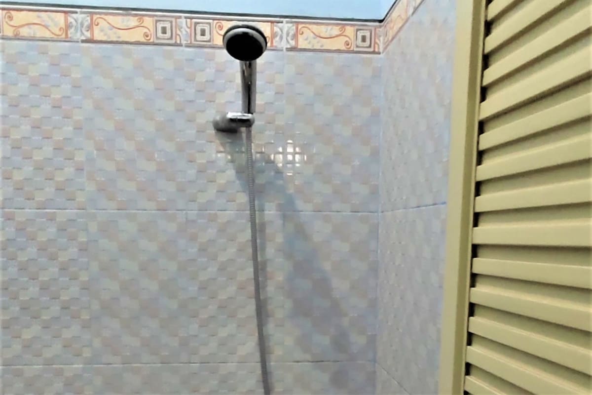 Eine Dusche mit Duschbrause und gefliestem Wandbereich mit Zierleiste.