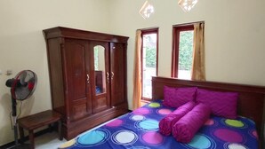 Un dormitorio con cama, armario, banco y dos ventanas.