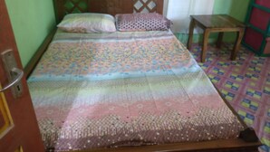 A bed with a patterned bedspread, pillows, and a wooden headboard. - Adji Homestay - Hostel (Muntuk)