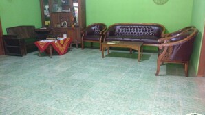 A living room with a sofa, two armchairs, a coffee table, and a small table with a red cloth. - Adji Homestay - Hostel (Muntuk)