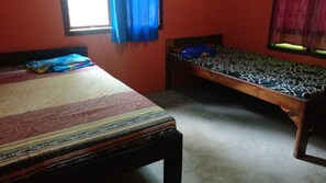 A room with two beds, one larger and one smaller, both with patterned bedspreads. - Klakat Bambu Homestay - Hostel (Muntuk)