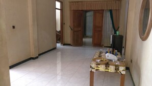 A spacious hallway with a tiled floor, a table with various items, and a door leading to another room. - Pringsewu Craft Homestay - Hostel (Muntuk)