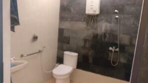 A small bathroom with a toilet, a sink, and a shower area. - Pringsewu Craft Homestay - Hostel (Muntuk)