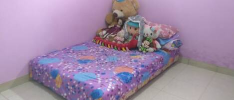 A small, neatly made bed with a colorful bedspread and a teddy bear on it.
