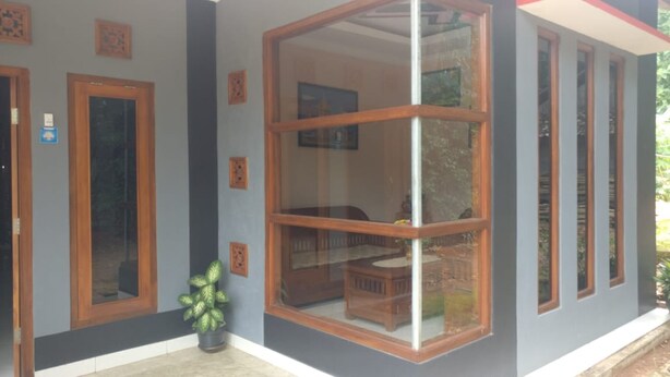 A house with a large glass sliding door, a small porch with a bench, and a potted plant. - Yati Homestay - Hostel (Muntuk)