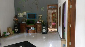 A room with a tiled floor, a wooden cabinet, a television, and a small desk. - Yati Homestay - Hostel (Muntuk)