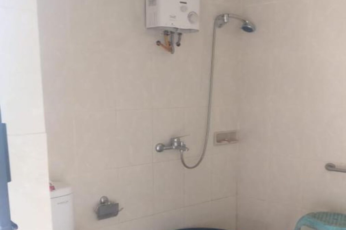 A small bathroom with a toilet, a shower, and a blue basin.