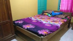 A bed with a floral bedspread, a wooden headboard, and pillows. - Wahyu Homestay - Hostel (Muntuk)