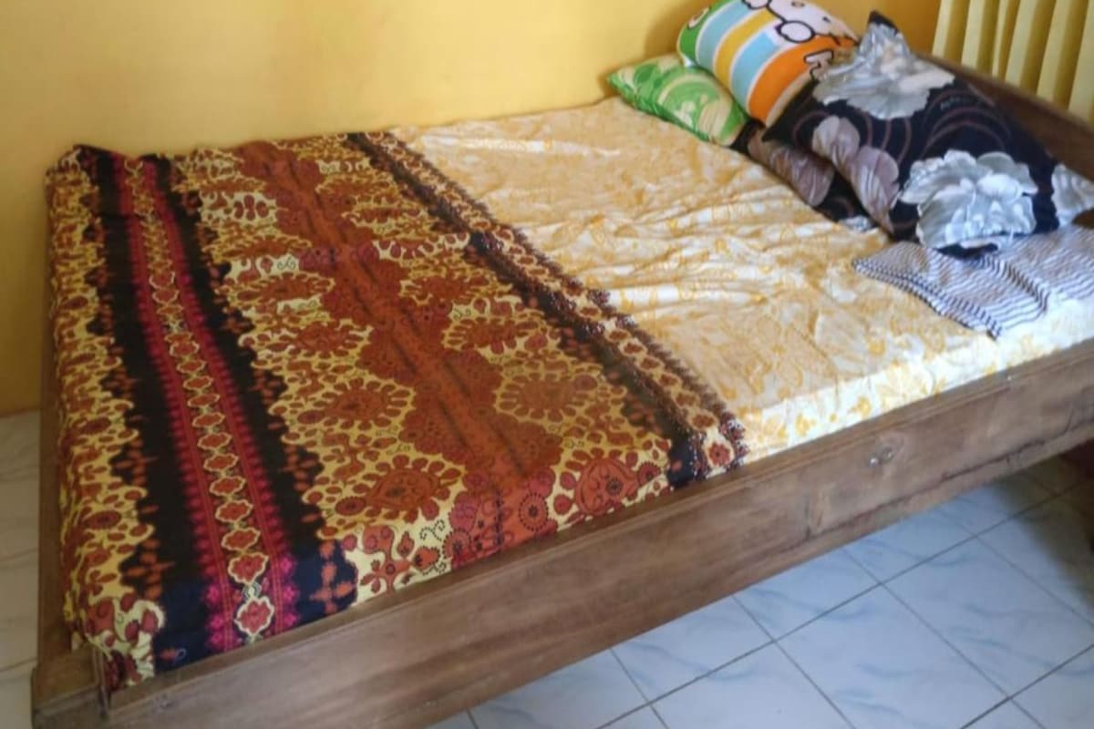 A bed with a patterned bedspread, pillows, and a blanket.