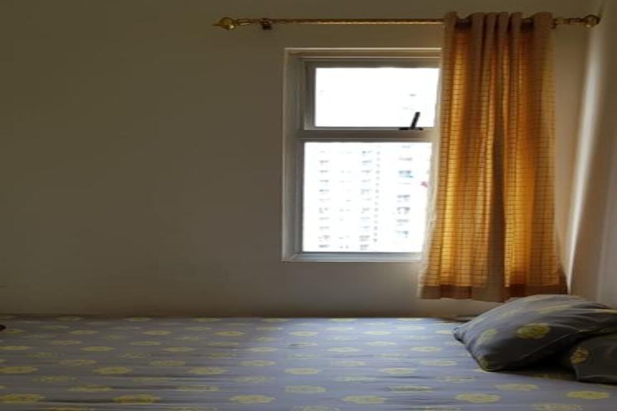 Une petite chambre avec un lit simple, une fenêtre et des rideaux.