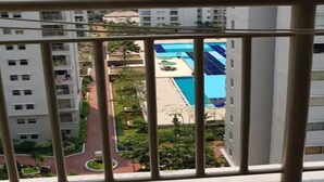 Een hoog appartementencomplex met diverse balkons en een zwembadgedeelte zichtbaar op de achtergrond.