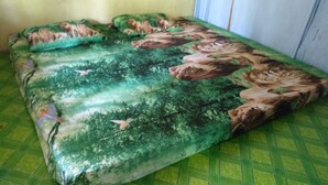 Un letto con coprimaterasso a tema foresta, nei toni del verde e del marrone.