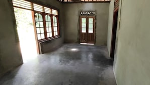 A corridor with a concrete floor, wooden doors, and large windows. - Natural Stone Homestay Syariah - Hostel (Bantul)