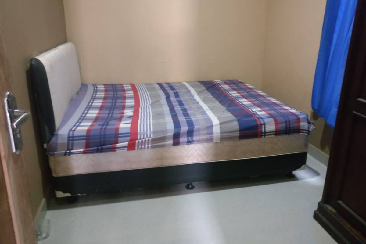 A small, single-bed room with a mattress and a headboard.