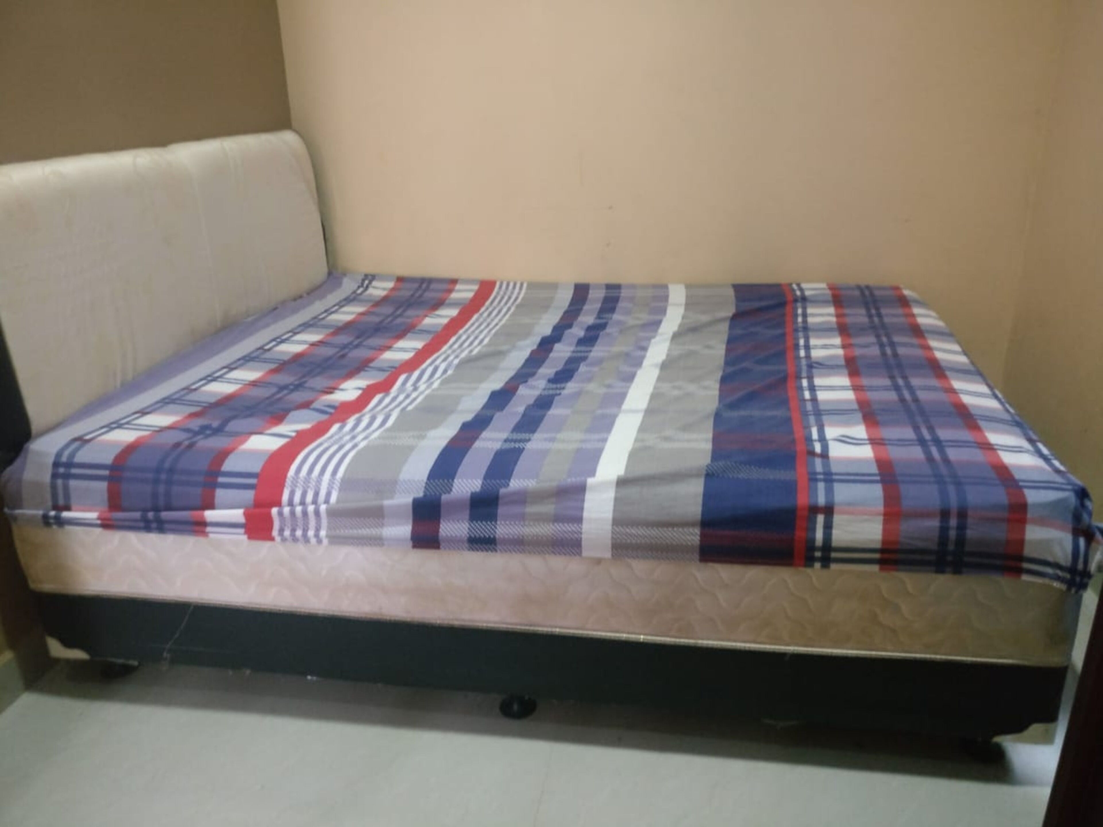 A small, single-bed room with a mattress and a headboard.