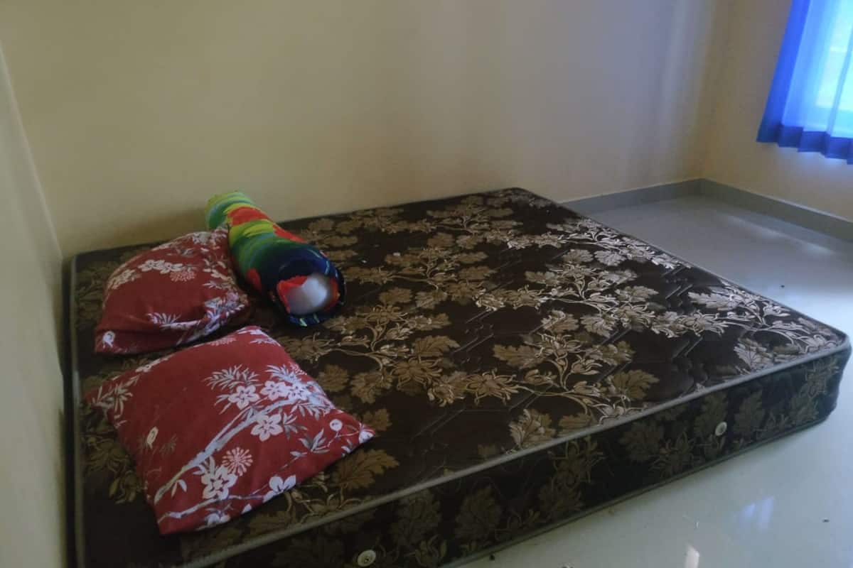 A mattress with floral patterns and two red pillows with white floral designs.