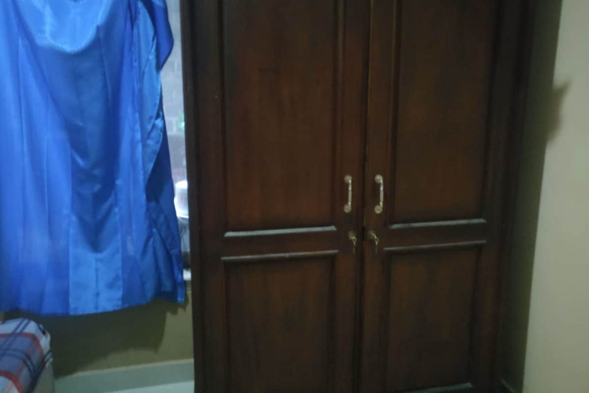 A room with a wooden wardrobe and a blue curtain.