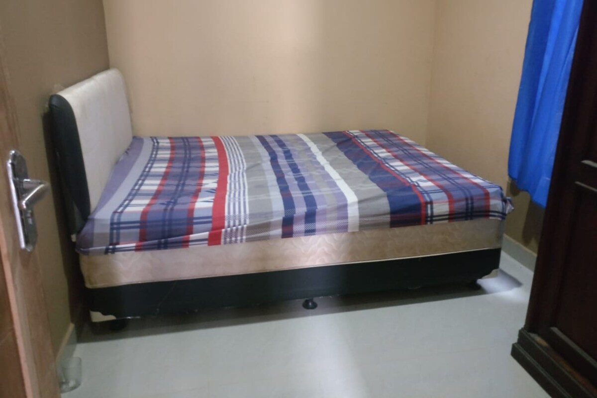 Une petite chambre avec un lit simple, un matelas et une tête de lit.