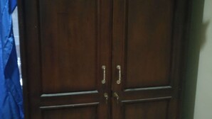 A dark wooden wardrobe with two doors and a handle on each. - Elvira Homestay - Hostel (Muntuk)