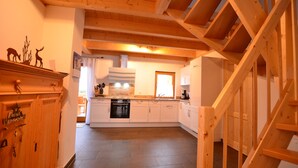 A kitchen with white cabinets, a stove, and a wooden staircase.