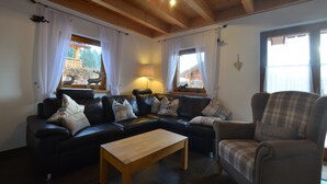 A cozy living room with a sectional sofa, a wooden coffee table, and a plaid armchair.