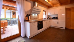 A modern kitchen with white cabinets, a built-in oven, and a large window with curtains.