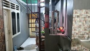Una cocina con un lavamanos, una cesta verde y una escalera que sube a un nivel superior.
