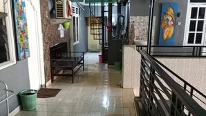 Un pasillo con pisos de baldosas, una pared verde, una escalera y una barandilla.