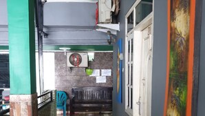 Un pasillo con suelo de baldosas, un banco, una puerta y una pared con un cuadro.