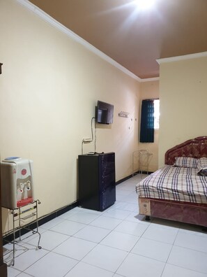 A bedroom with a bed, a television mounted on the wall, a water dispenser, and a small table. - Griya Sekar Wangi (Surabaya)