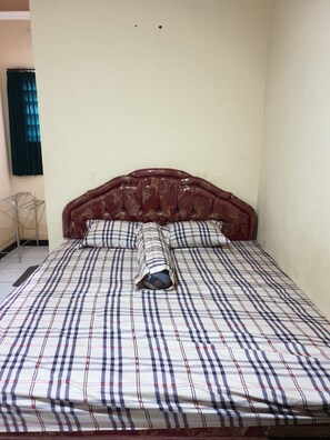 A bed with a checkered bedspread and a headboard with a floral pattern. - Griya Sekar Wangi (Surabaya)